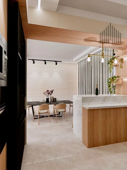 A view from the dining area into the kitchen, showing the integrated design with a breakfast bar, built-in appliances, and track lighting.