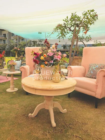A comfortable lounge area for a welcome lunch, with pink armchairs and eclectic cushions set up on the lawn.