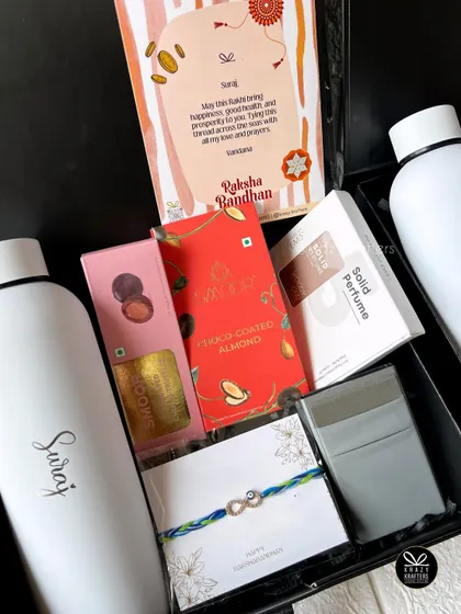 A modern Rakhi hamper for a brother, including a personalized water bottle, solid perfume, a wallet, chocolates, and an evil eye rakhi.