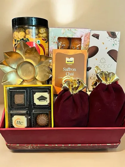 This festive tray is filled with a variety of treats perfect for corporate Diwali gifting. It includes custom-branded chocolates, saffron chai, savory snacks, and a beautiful brass flower diya.
