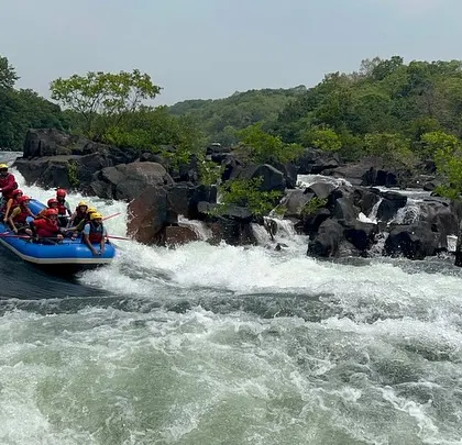 A wide shot of a raft approaching a natural drop on the Kali River. This highlights the stunning and dramatic landscapes you'll encounter during our Dandeli summer camps.