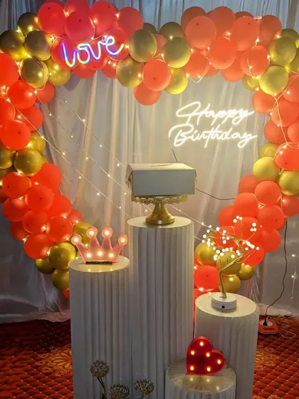 A romantic heart-shaped balloon arch in red and gold, perfect for a birthday or anniversary celebration.