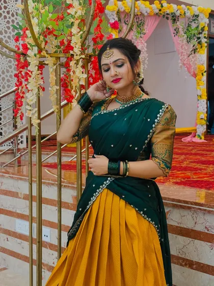 A full view of the elegant green and mustard half saree, a classic choice for wedding guests. The outfit is styled with traditional jewelry for a complete look.