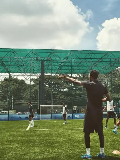 A coach directs players during a tactical session on the pitch. We work on shape, positioning, and movement to build a cohesive team unit.