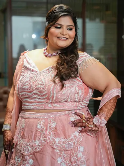 A three-quarter shot of the bride, highlighting her intricate henna and the details of her outfit.