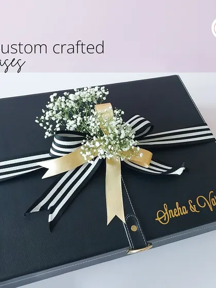 Custom crafted cases that make a statement. This black leather-style box is personalized with the couple's name and finished with a striped ribbon and a sprig of baby's breath.