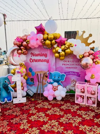 This photo highlights the various elements of the setup, including the light-up number '1', the character cutouts, and the gold pedestal for the cake.