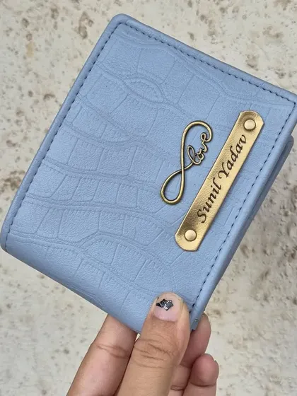 This sky blue wallet with a crocodile texture is personalized with a name and an infinity love charm, making it a wonderful gift for a loved one.