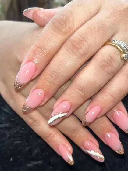 A glamorous take on a classic pink manicure, these almond-shaped nails feature sparkling gold glitter tips and delicate white line accents. This design is perfect for weddings, parties, or any festive event.