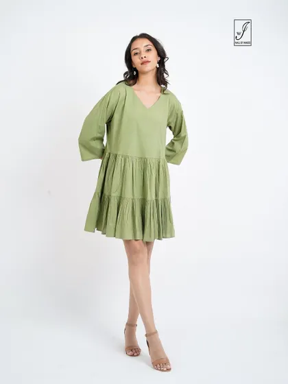 A simple standing pose that clearly shows the v-neck and tiered design of the dress.