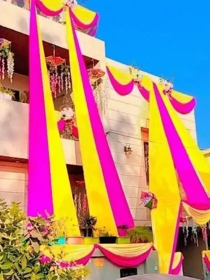 A bright and sunny view of a house decorated with long pink and yellow drapes for a daytime wedding event.