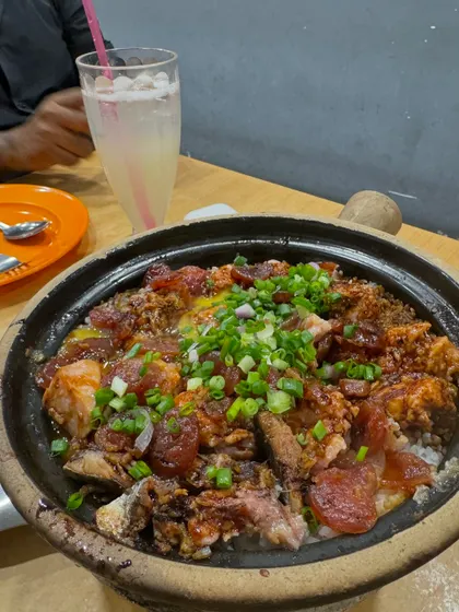 A sizzling claypot filled with rice, chicken, and Chinese sausage, topped with fresh green onions. This traditional cooking method creates a wonderful crispy rice layer at the bottom of the pot, which we call 'fan chiew'.
