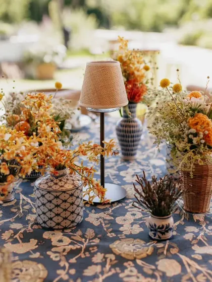 A tablescape featuring a mix of patterned linens and vases. The small table lamp adds a cozy, intimate feel, perfect for encouraging conversation among guests.