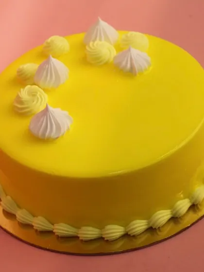 A bright and sunny Pineapple Cake with a smooth yellow glaze and delicate white piping.