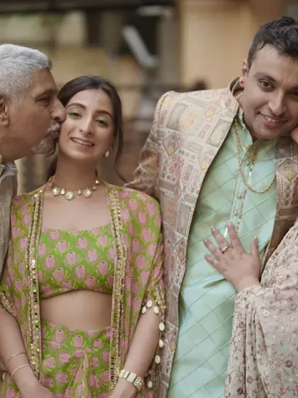 A heartwarming family portrait, with the parents kissing the bride and groom on their cheeks.