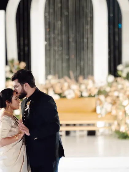 A tender moment between the couple on their reception stage. The modern black and white decor with soft floral accents creates a chic and sophisticated ambiance.