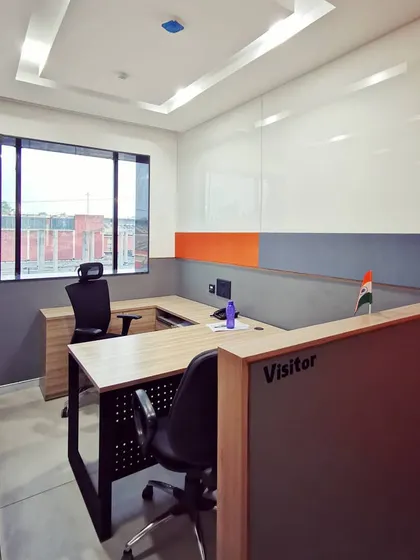 A semi-private workstation, offering a balance between an open-plan layout and individual focus. The design uses partial-height partitions and a clean color palette of white, grey, and orange.