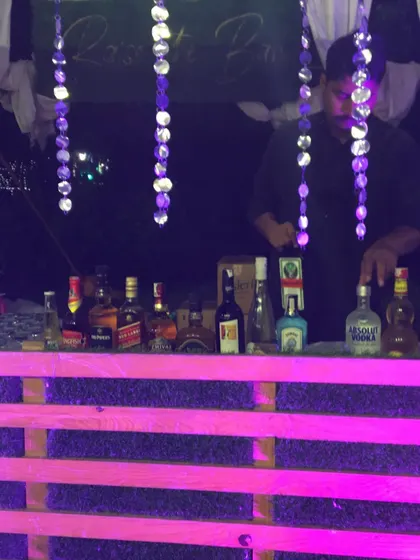 A bartender at our rustic pink bar, preparing drinks with a full selection of spirits.