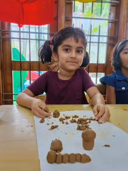 A young girl proudly shows her clay caterpillar and mushroom creations. Our clay modelling sessions allow children to turn their imagination into 3D art.