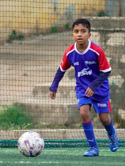 A young player looks up while dribbling, demonstrating good awareness. We teach our players to scan the field and make smart decisions.