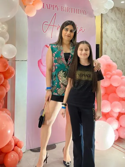 The birthday girl posing with a guest in front of the personalized backdrop.