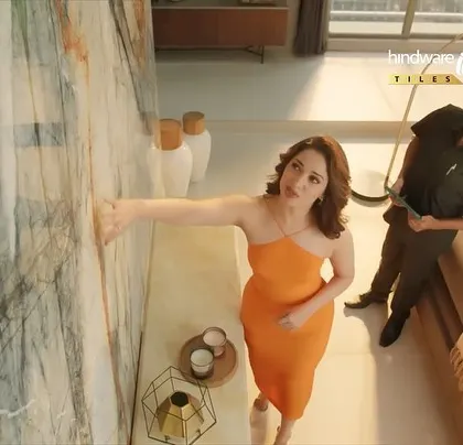 Tamannaah inspecting the tiles in the Hindware ad. The high-angle shot provides a great view of her dress and the product.