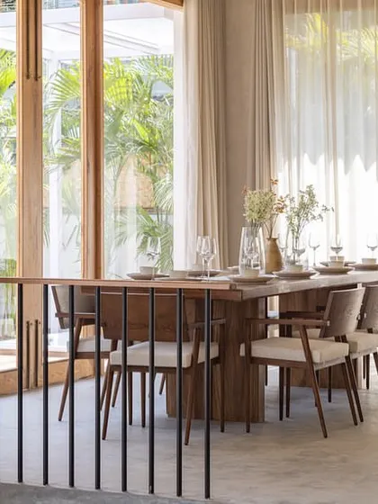 The open-plan kitchen and dining area in the House of Basho. We used a mix of warm wooden finishes and cool concrete countertops, along with high ceilings and large windows, to create an expansive and light-filled retreat feel.