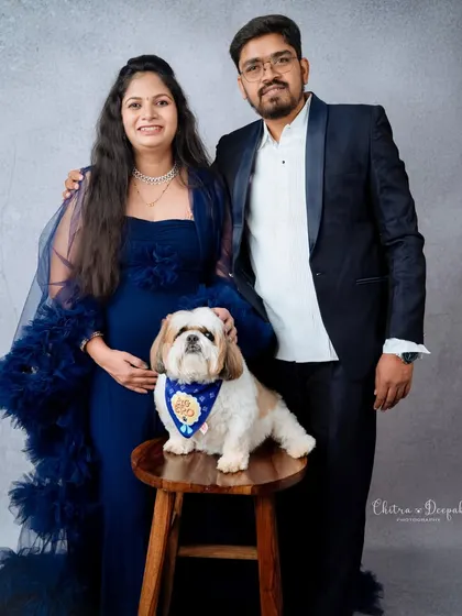 A formal family portrait with their furry best friend. This well-dressed pup is clearly a cherished member of the family.