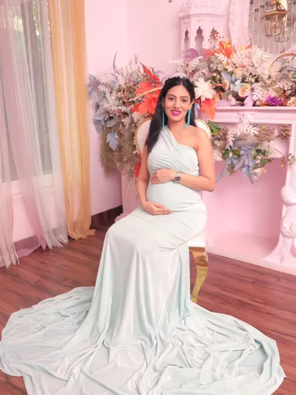 The mom-to-be seated gracefully, her gown flowing around her. This pose highlights the beauty of pregnancy in a serene and classic style.