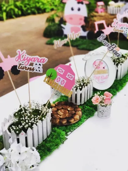 A closer view of the adorable, handcrafted centerpieces on the children's dining table. These little details, from the picket fences to the custom signs, help create a cohesive and immersive farm party experience.