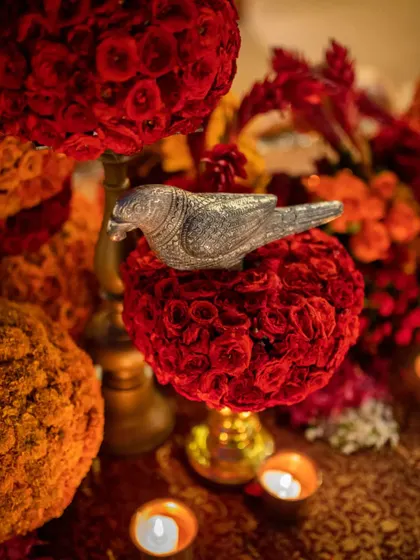 Another beautiful detail of a silvered bird resting on a ball of deep red roses, surrounded by the soft light of candles.
