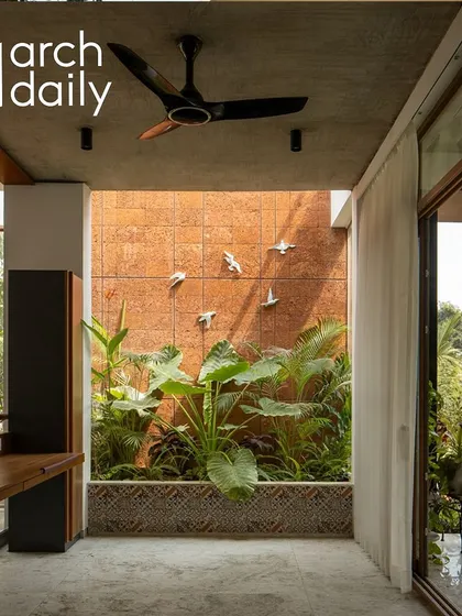 An interior courtyard space featuring a laterite wall and tropical plants. These small green pockets bring light, air, and life into the core of the home.