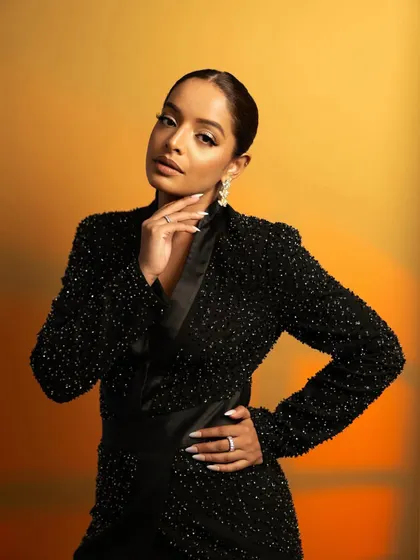 A classic, elegant pose that radiates confidence. This shot highlights the plunging neckline of the blazer dress and the sparkling earrings.