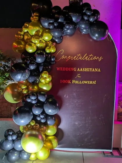 This angle shows the depth of the organic balloon garland against the backdrop. The mix of large and small balloons in black and gold creates a dynamic and textured look for corporate branding.