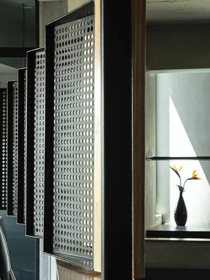 In our own studio, 'Project 113', we used pivoted louvers made of perforated steel and birch ply to create a flexible partition. This detail, captured here with sunlight creating sharp shadows, is an example of how we experiment with materials and light.