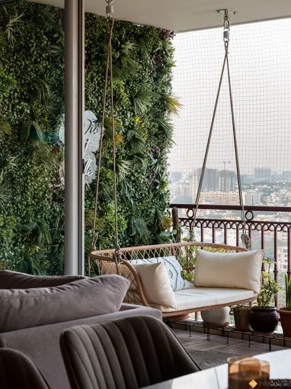 A view from the living room to the balcony, showing the inviting swing against the backdrop of the city. The green wall creates a private, garden-like feel.