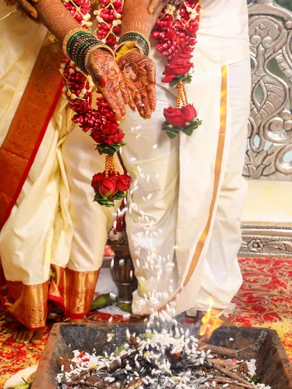 A close-up detail shot of offerings being made to the sacred fire during a Hindu wedding ceremony.