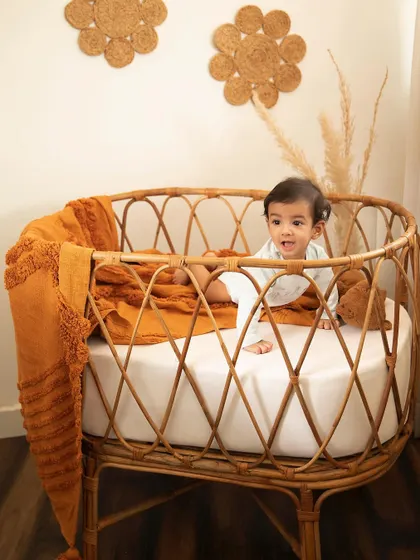 A boho-themed sitter session in my studio. This little one is exploring the beautiful cane bassinet, full of smiles and curiosity.