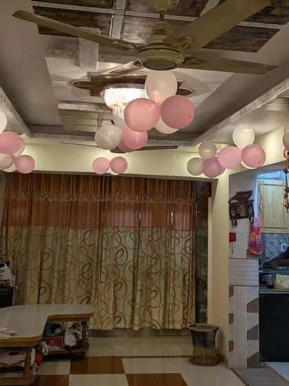 A candid shot of the living room space with simple pink and white balloon decorations on the ceiling, showing how I can work in any home environment.