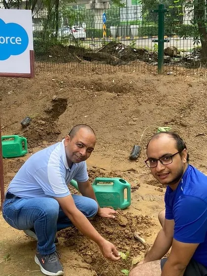 Two smiling volunteers from Salesforce plant a native sapling, helping to restore a vital green corridor in Gurgaon.