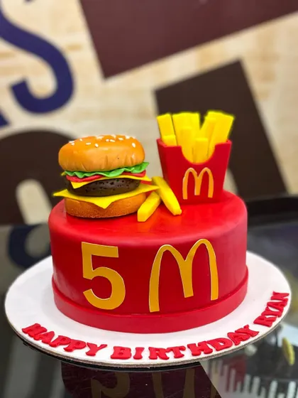 A fun and unique creation, this 3kg cake is designed for a fast-food lover. It features a bright red base with the iconic golden arches and is topped with an incredibly realistic, fully edible fondant burger and fries.