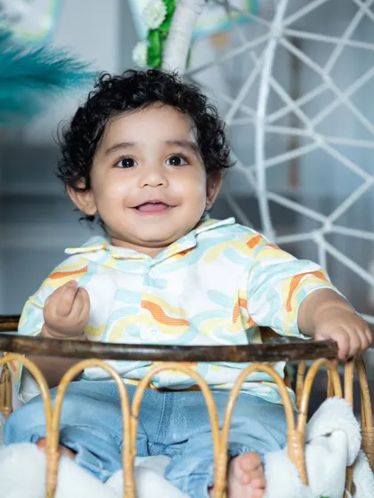 A bright and happy smile from this little one, sitting in a wicker chair.