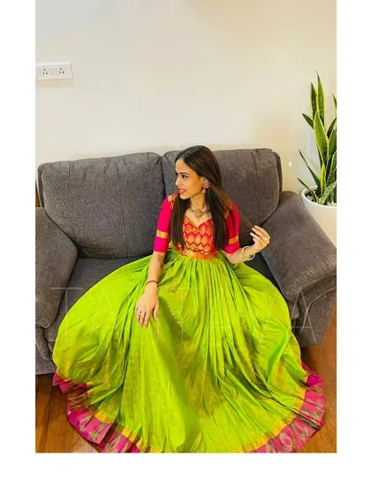 The full, flowing skirt of this upcycled saree dress creates a grand look, even when seated. The bright lime green is perfectly complemented by the traditional pink border.