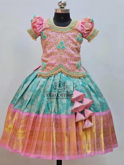 A pastel Kanchipattu lehenga with a pink blouse. The blouse features delicate floral embroidery in a contrasting light blue thread.