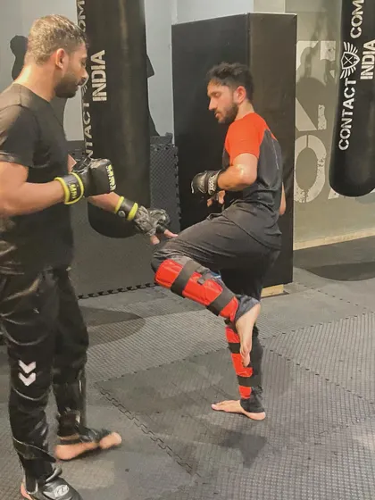 An instructor works one-on-one with a student, correcting his kicking technique. This personalized feedback is crucial for developing proper form and maximizing power.