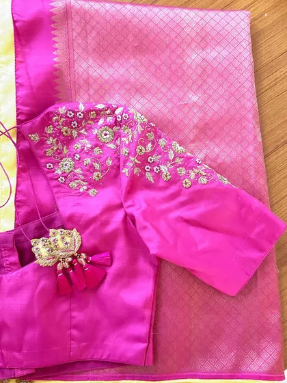 A pink raw silk blouse with minimal yet elegant embroidery details on the shoulder and a beautiful tassel tie-up.