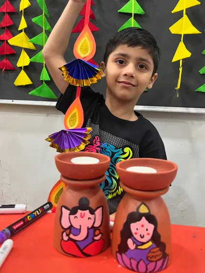 A proud student with his completed Diwali crafts, ready to decorate his home.