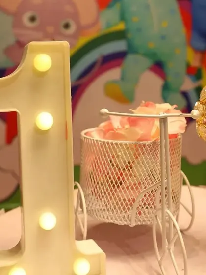 A close-up of the small details that make a party special. This light-up number '1' is paired with a decorative miniature bicycle and a crystal candle holder.