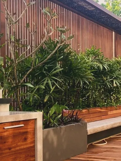 A terrace seating area with built-in planters and a wooden screen for privacy. This design transforms a simple balcony into a functional and beautiful outdoor living room.