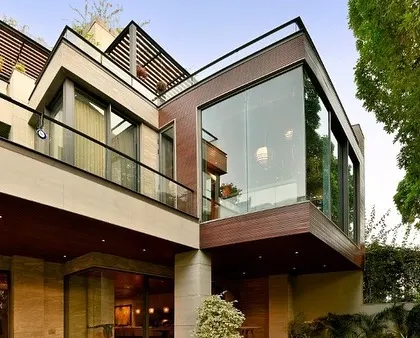 The facade of this modern Gurgaon home is a composition of intersecting planes, materials, and voids. The design uses balconies, large windows, and recessed volumes to create a dynamic and visually interesting exterior that still feels warm and residential.